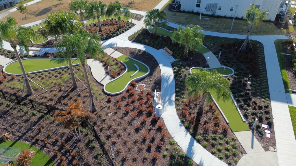 Lush landscaped outdoor space with winding concrete pathways and palm trees.