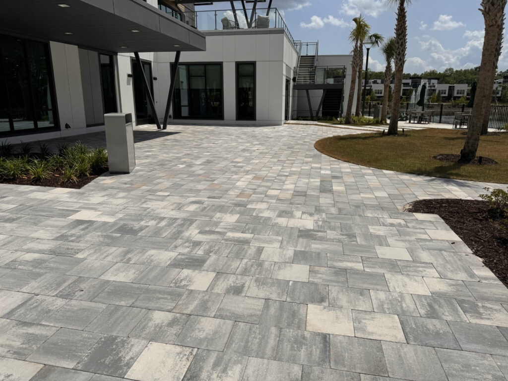 Modern outdoor sunshade with lounge chairs and landscaped garden in a residential complex.