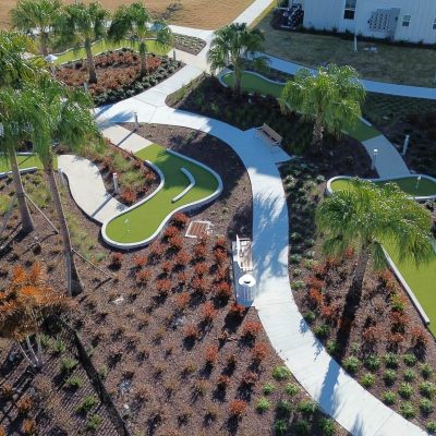 Lush landscaped outdoor space with winding concrete pathways and palm trees.