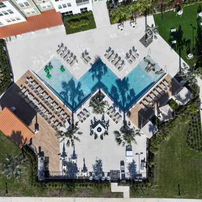 Swimming pool with lounge chairs and surrounding outdoor hardscapes, aerial view.