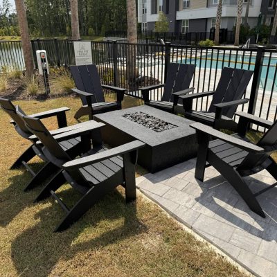 Stylish black Adirondack chairs surrounding a fire pit on a landscaped outdoor patio.